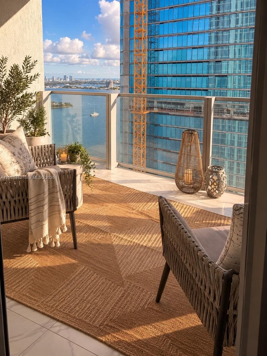 Private balcony featuring light-toned tile flooring and a glass-paneled railing