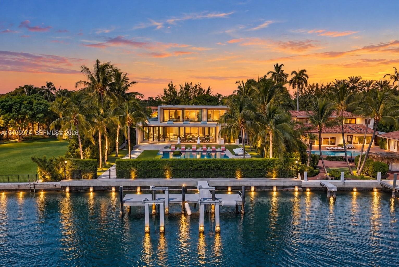 Waterfront estate featuring a deep-water dock, multi-level exterior architecture with floor-to-ceiling glass, an expansive swimming pool, and manicured landscaping