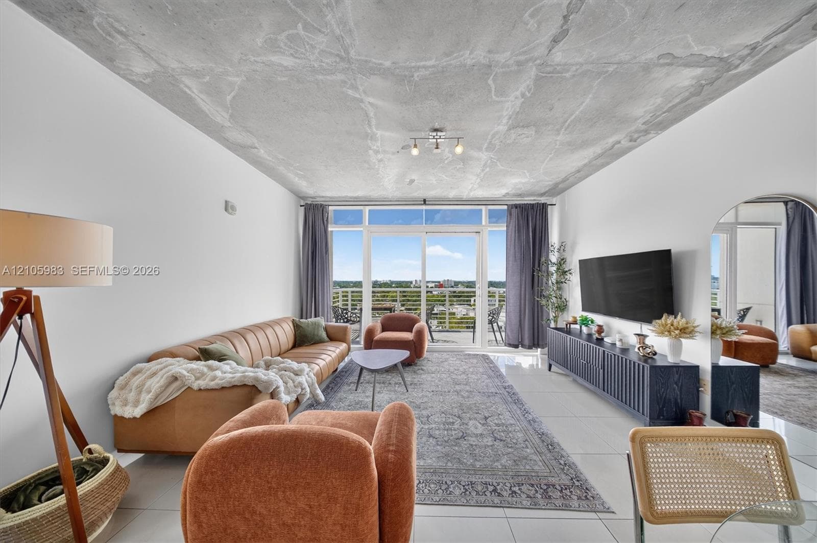 Exposed concrete ceiling, tile flooring, and floor-to-ceiling glass sliding doors opening to an exterior balcony