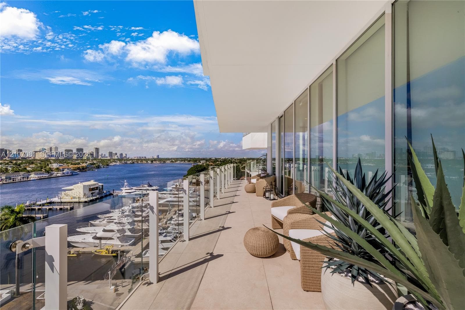 Expansive covered balcony featuring glass railing, smooth concrete flooring, and floor-to-ceiling windows