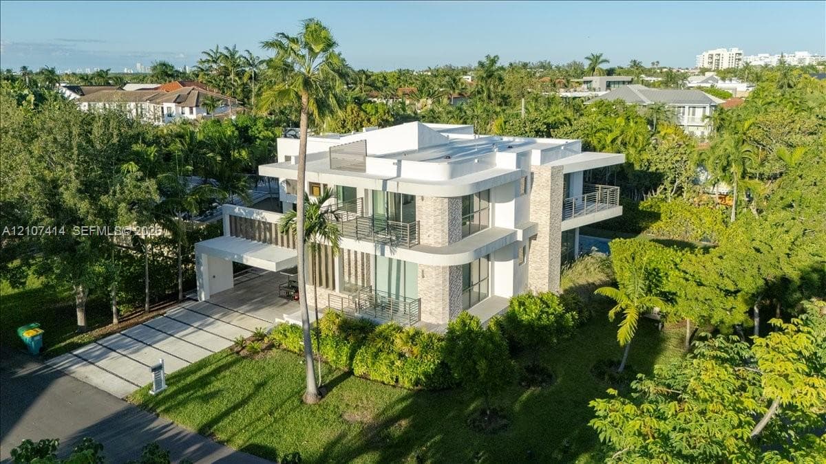 Modern multi-level residence featuring a concrete exterior, stone veneer accents, multi-level balconies with metal railings, and a paved driveway