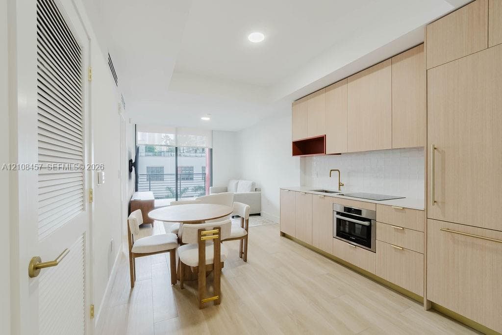 Kitchen featuring light wood-finish cabinetry, quartz countertops, an integrated refrigerator, recessed lighting, and wood-finish flooring